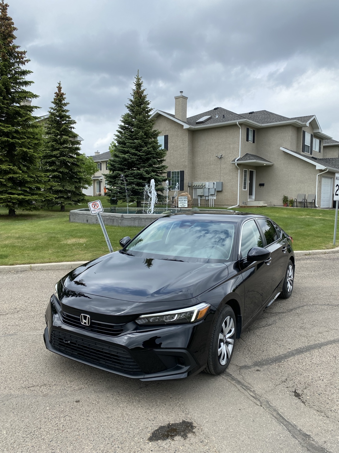 Black Honda sedan with glossy exterior finish parked outdoors under cloudy skies.