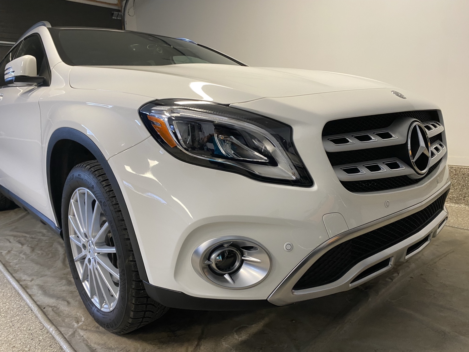 White Mercedes SUV front three-quarter view with clean paint and bright finish in garage.