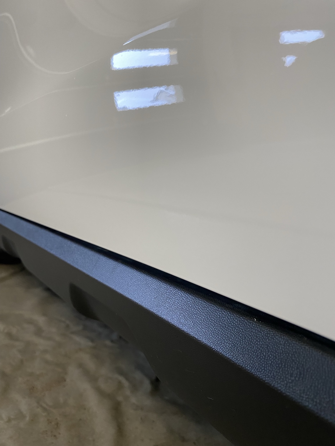 Close-up of restored black lower trim on a white Mercedes vehicle.